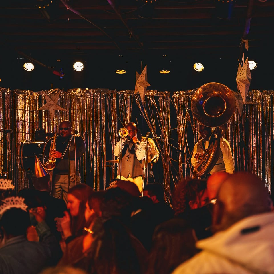 Live brass band performs beneath star decorations and warm lights before a lively crowd.