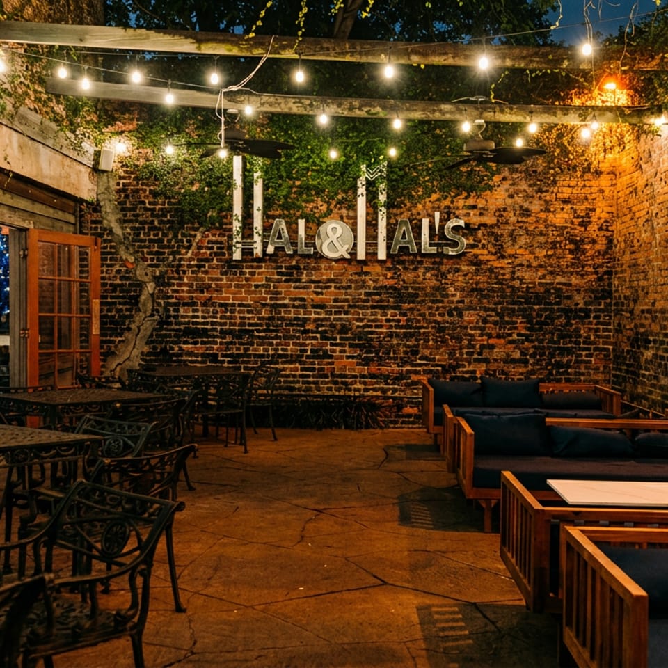 Hal & Al's outdoor patio at night, with string lights, brick walls, and various seating.